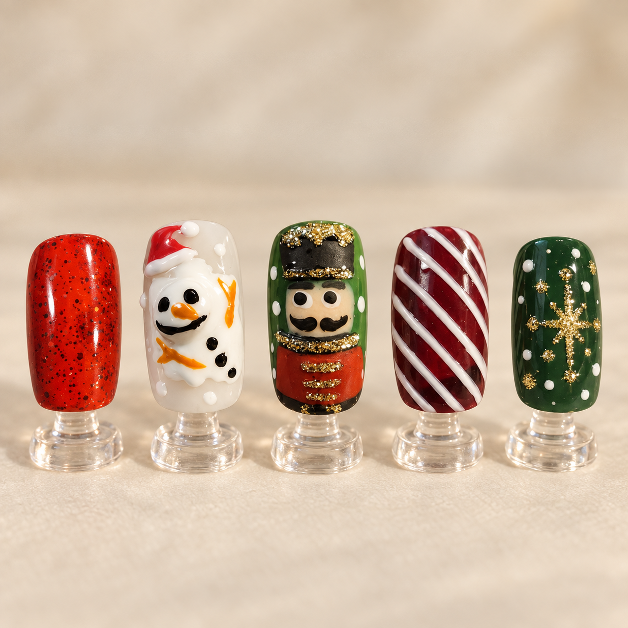 Hand painted snowman toy soldier candy stripe and red glitter nail art displayed on clear stands