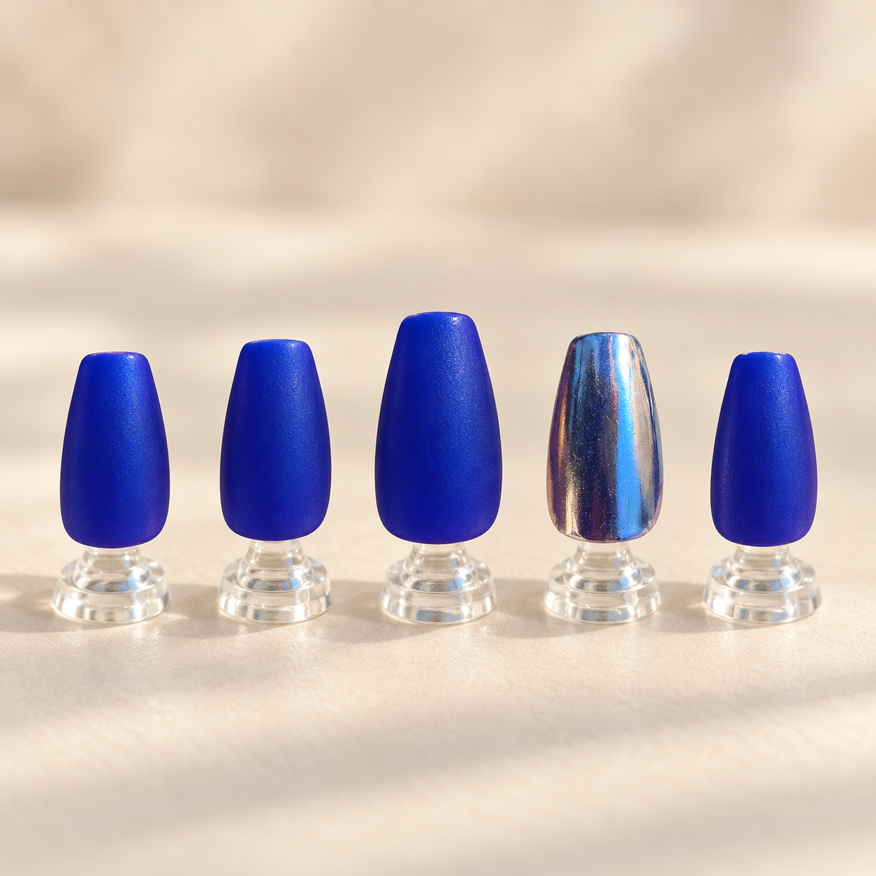 Royal blue matte and reflective chrome nail art displayed on clear stands