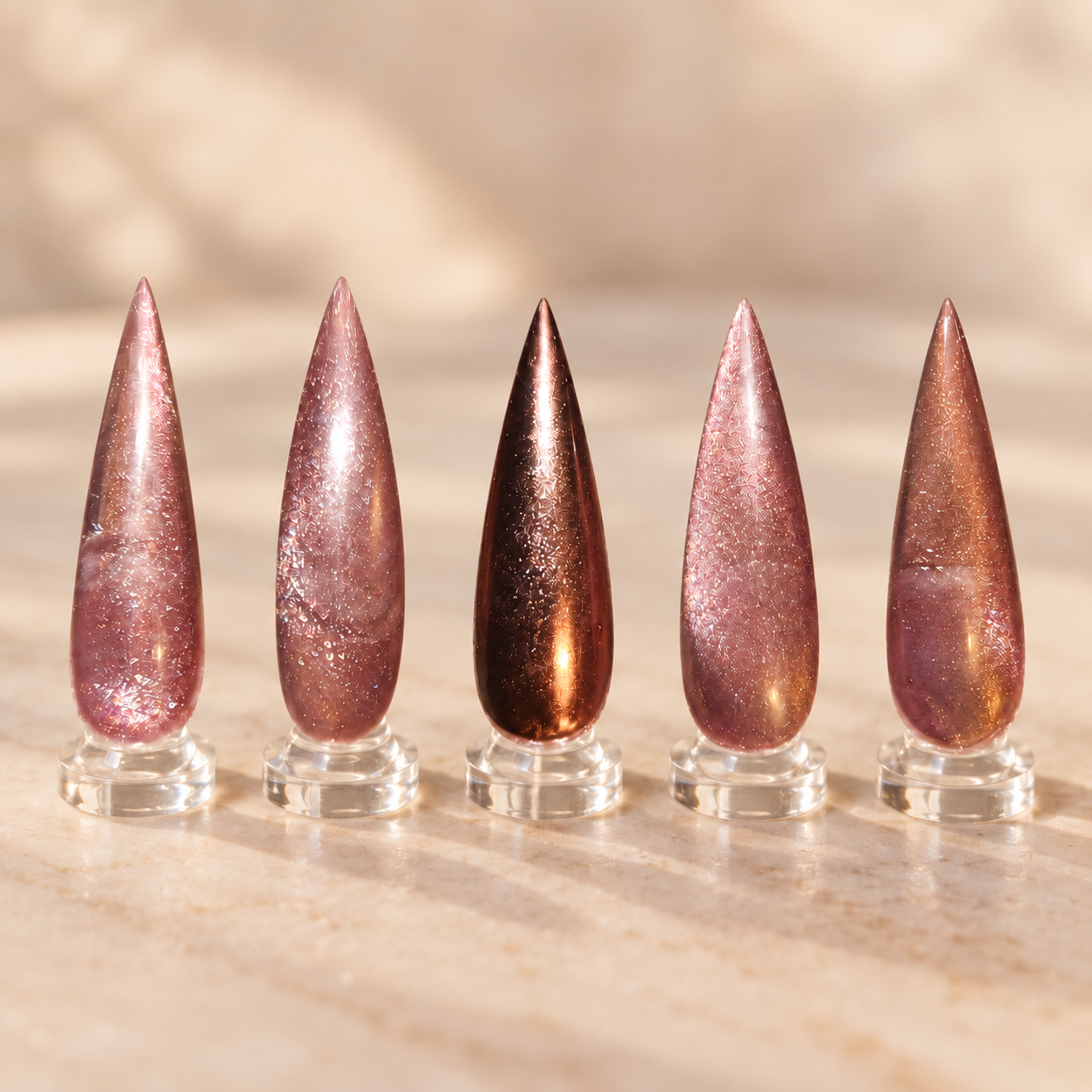 Rose bronze mauve and chocolate magnetic cat eye stiletto nails displayed on clear stands