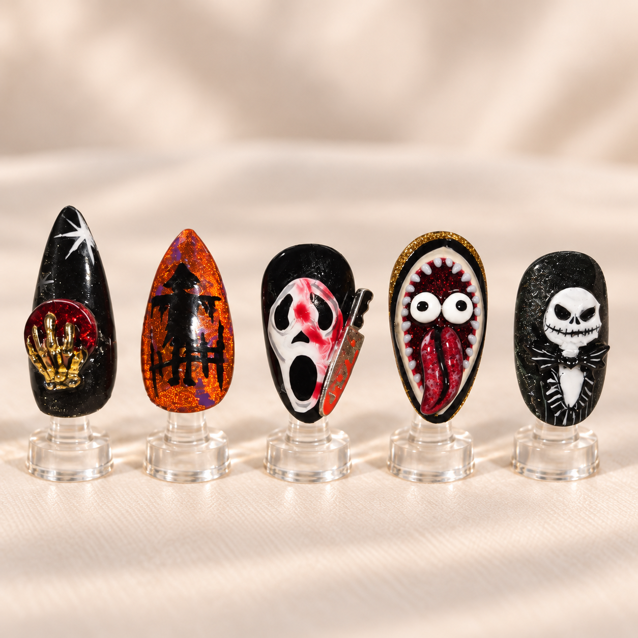 Halloween horror nail art with a crystal ball scarecrow Ghostface knife Beetlejuice character and Jack Skellington displayed upright on clear stands