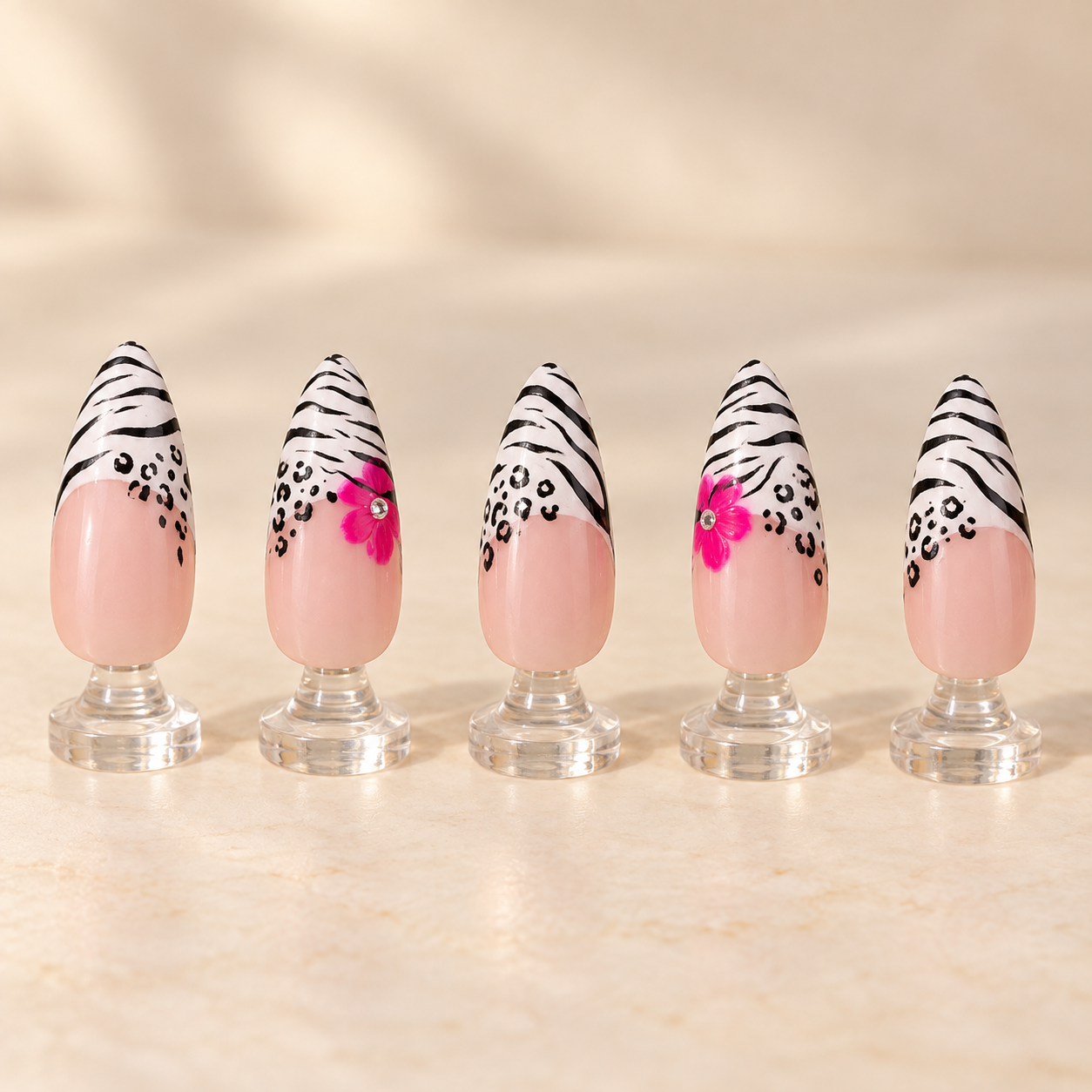 Zebra and leopard French tip nail art with bright pink flowers displayed on clear stands