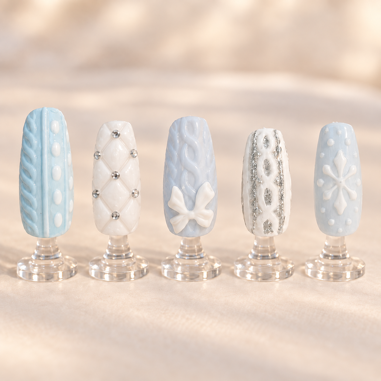 Icy blue and white winter nail art with molded sweater textures crystals and raised details displayed on clear stands